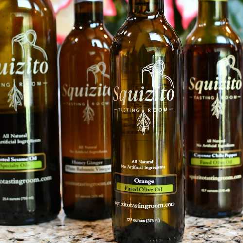 Bottles of squizito tasting room flavored olive oils with labels in focus, showcasing premium, artisanal olive oil branding for the e-commerce website